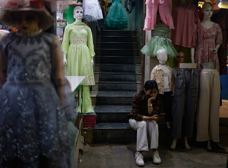 KILLING TIME: A clothing vendor waits for customers on Wednesday evening in Lagankhel, a week ahead of Dasain when it should have been busy with shoppers. Businesses have reported a decline in sales despite the upcoming festive season. Photo: GOPEN RAI