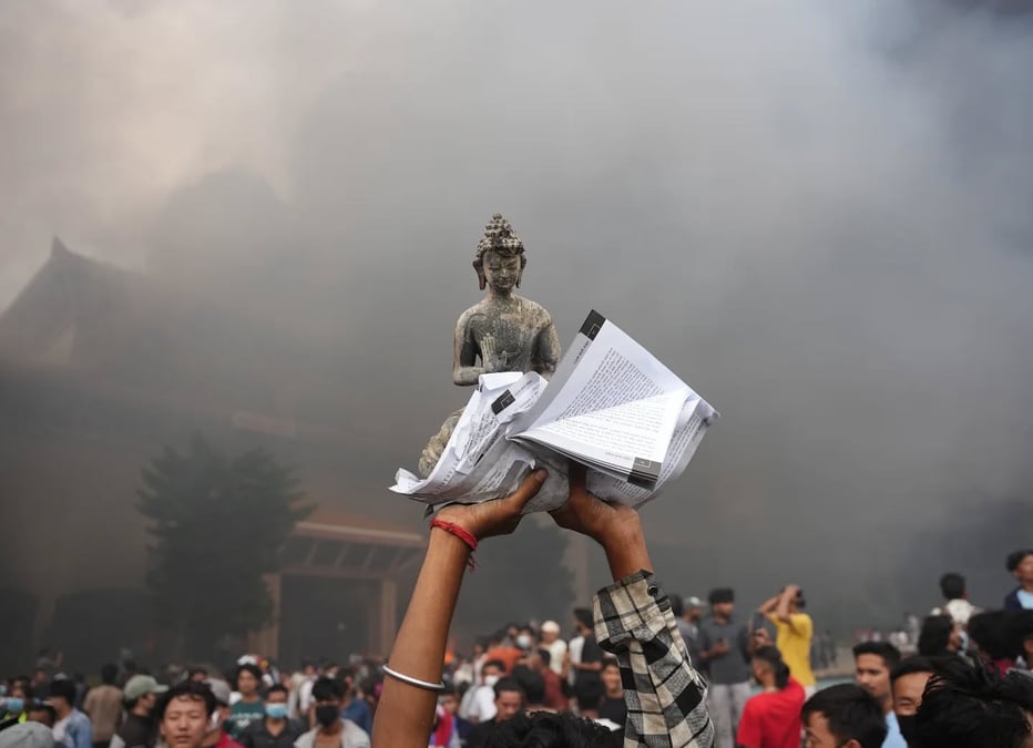 Demonstrators held aloft a Buddha statue outside the torched Parliament building on Tuesday. Photo: AMIT MACHAMASI